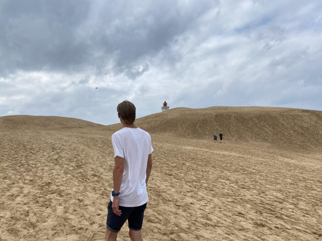 Mand på gåtur ved Rubjerg Knude og kigger op mod fyret