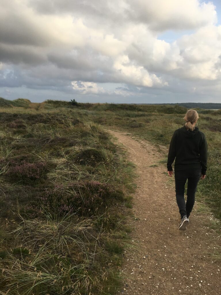 Person går ned ad en jordsti i et åbent naturområde