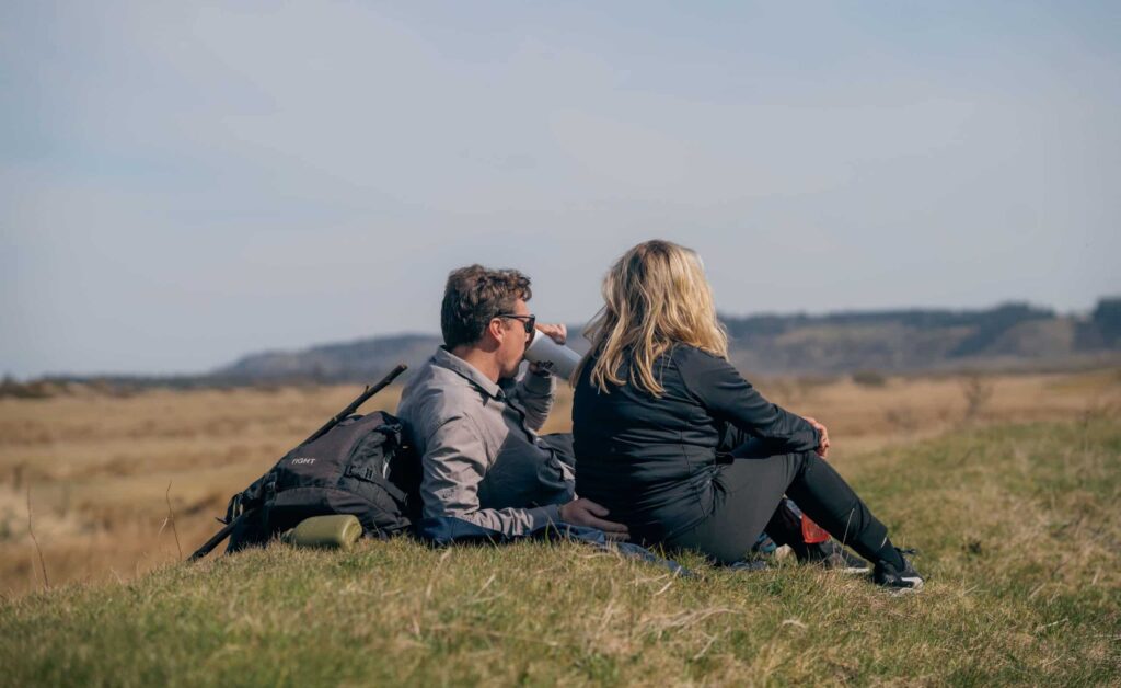 Par holder pause på bakketoppen samtidigt med at de nyder udsigten ud over landskabet