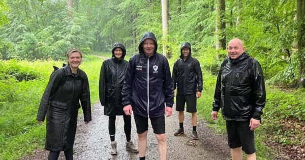 Fem personer på vandretur i skoven i regnvejr
