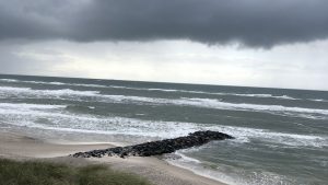 Havet ved østkysten under en grå himmel, hvor solen bryder igennem i horisonten