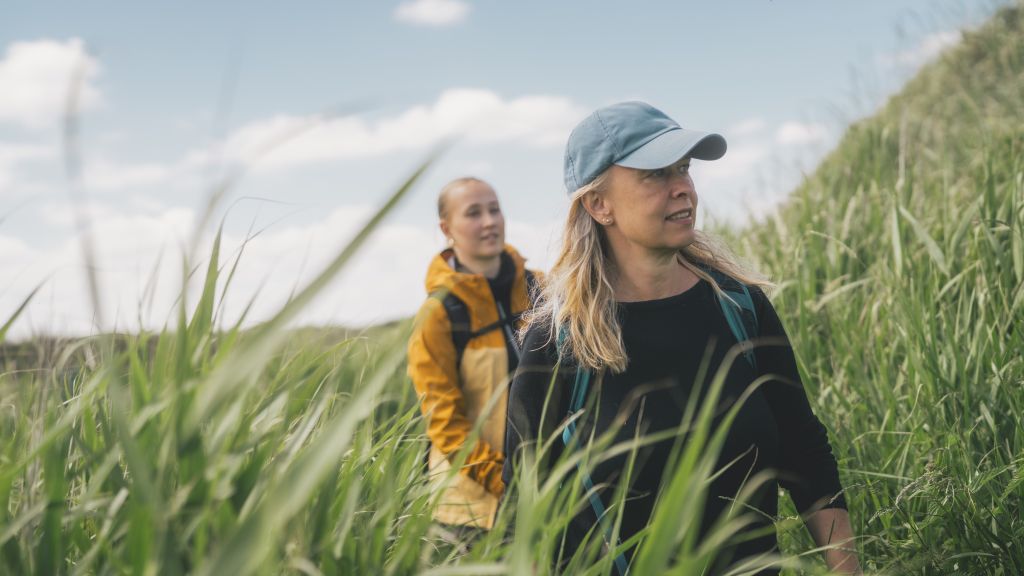 To kvinder går gennem sivene ved kysten