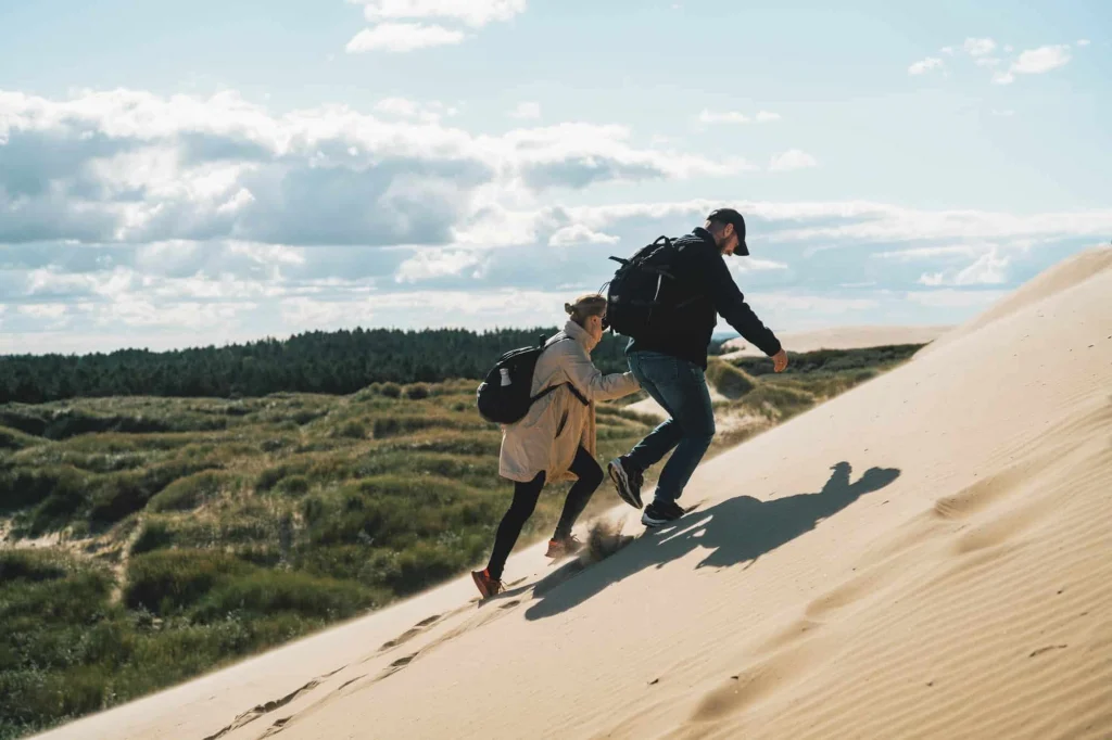 Kvine og mand går op ad sandklitterne ved Rubjerg Knude