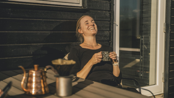 Kvinde nyder en kop kaffe i solen på terassen