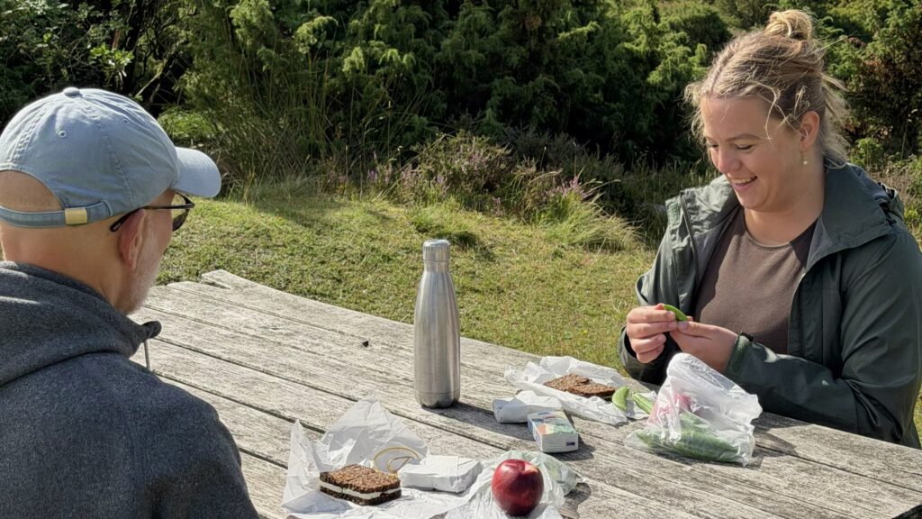 Kvinde og mand spiser madpakke på en bænk i Rold Skov